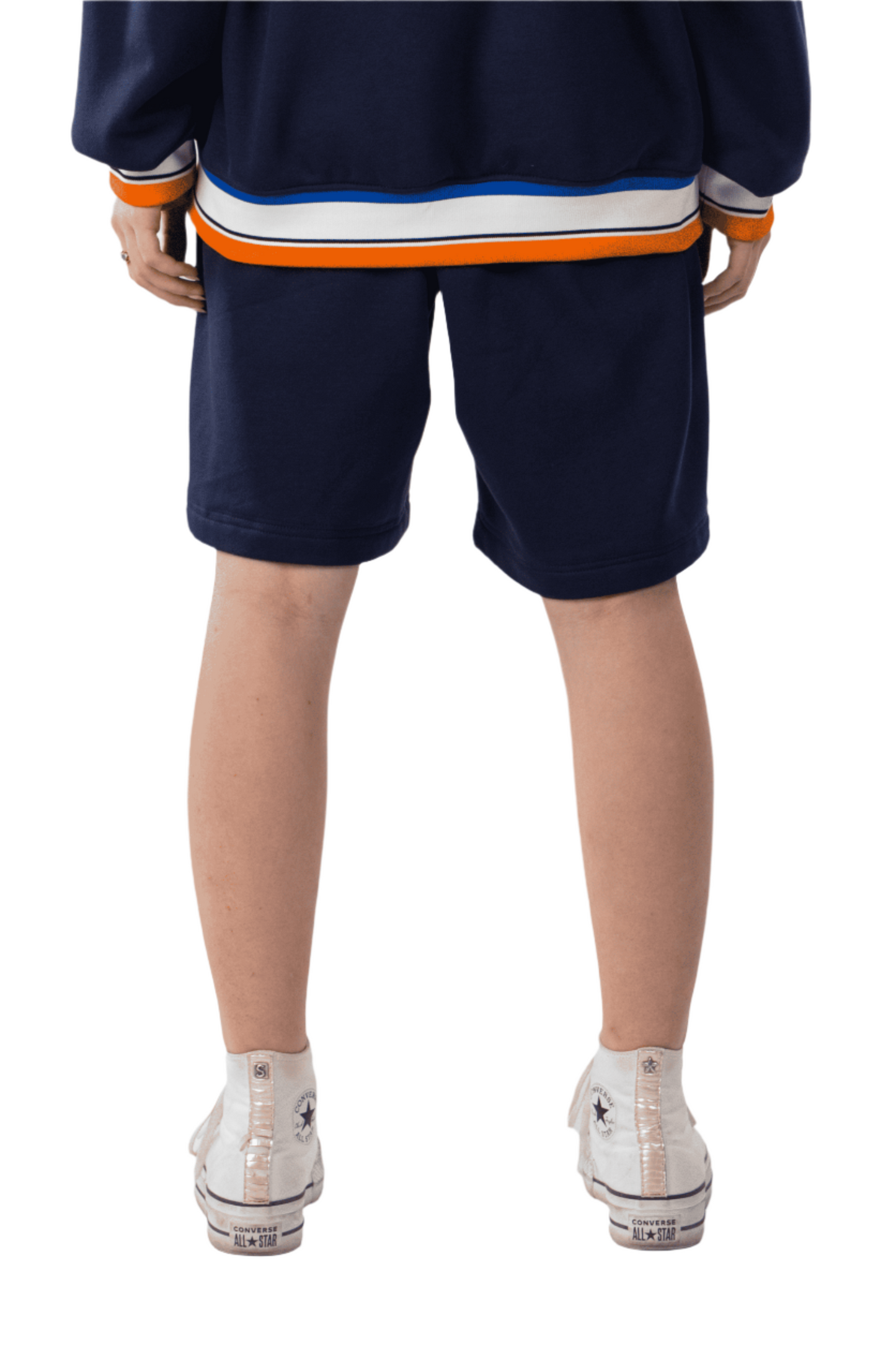 Person wearing a navy hoodie and shorts with colorful stripes on a white background